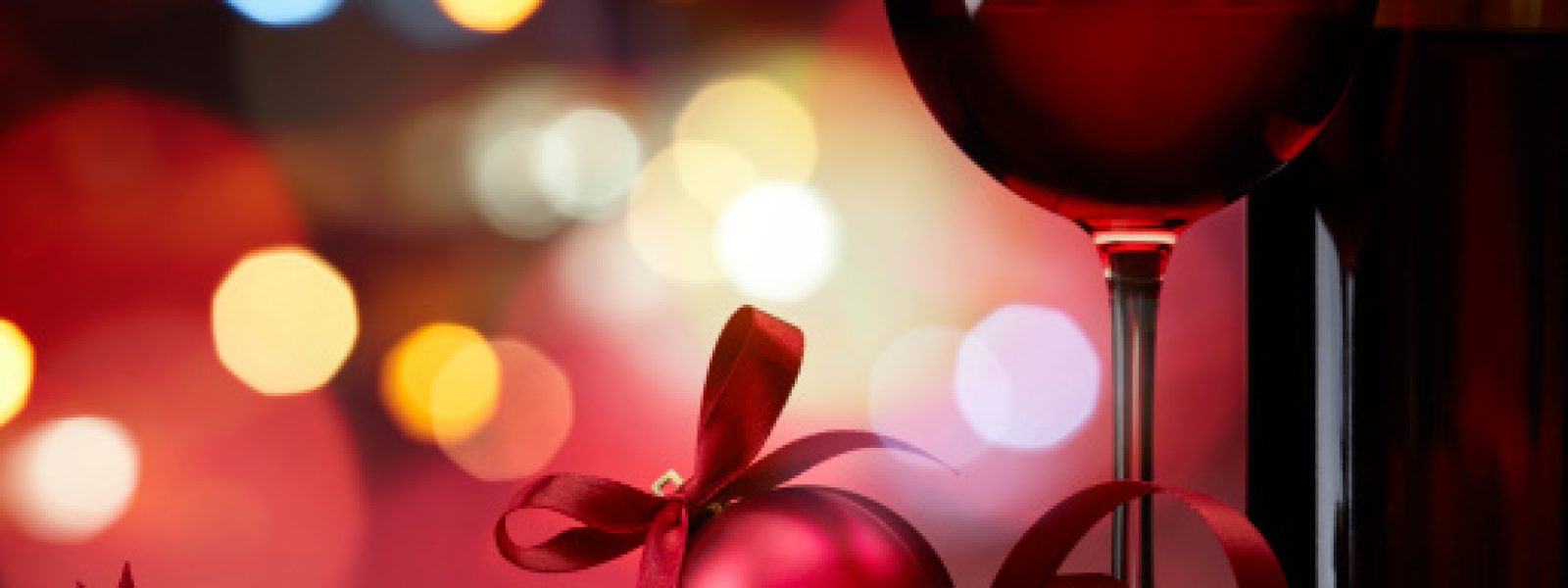 christmas bauble with red wine against colorful bokeh lights background